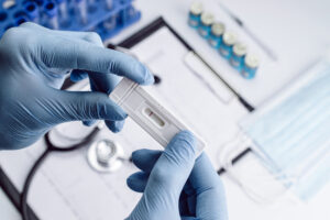 A doctor wearing blue gloves examines a test strip